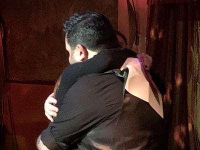 Audience member hugs Mike Paldino on stage during Mike Paldino: Modern Oracle at Ruba in Philadelphia.
